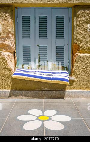 Part of modern building. Window with closed shutters. Architecture. Exterior, fragment. Flower painted on tiled floor outdoor. Place to sit down on Stock Photo