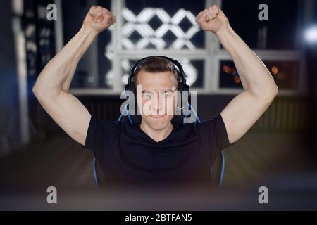 Portrait of ecstatic gamer guy in headphones screaming and rejoicing while playing video games on computer Stock Photo