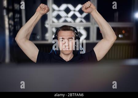 Portrait of ecstatic gamer guy in headphones screaming and rejoicing while playing video games on computer Stock Photo