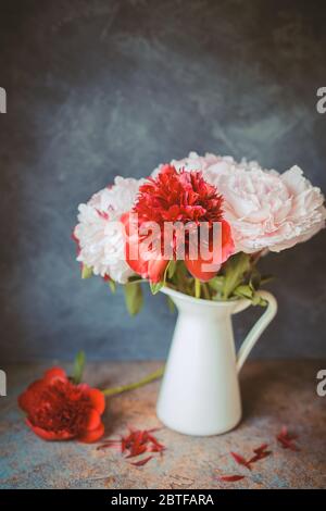 Toned photo. Vase with bouquet of beautiful peonies on table in room, close-up. Bloom. Peony.  Stock Photo