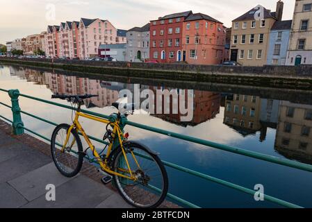 Old rusty Yellow mountian bicycle attached to metal gate railing by the river lee in Cork city Stock Photo