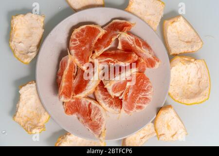 slices of grapefruit on a plate, a thick peel of fruit lies around the plate Stock Photo