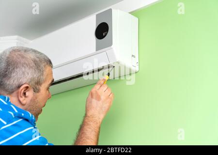 Male technician repairing and diagnosing air conditioners. Diagnostics for errors and preparation of a repair plan Stock Photo