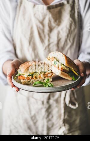 Woman holding plate with fresh fried fish sandwich with lemon Stock Photo