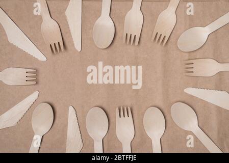 Top above overhead view photo of wooden cutlery lying sideways making center empty isolated on craft paper background Stock Photo