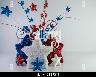 Red, white and blue tinsel stars with glitter stars in front and glitter swirls and stars coming up behind it on a white background for Memorial Day, Stock Photo