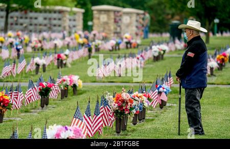 Bear, Delaware, USA. 25th May, 2020. A visitor walks among the grave stones and flags while paying respects on Memorial Day. While the Delaware VeteranÕs Memorial Cemetery did not hold their annual Memorial Day remembrance service, many showed up with masks and observing social distancing to pay respects and remember loved ones during the coronavirus pandemic. Scott Serio/ESW/CSM Credit: Cal Sport Media/Alamy Live News Stock Photo