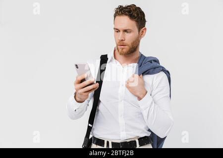 Image of focused blonde man holding jacket and typing on cellphone isolated over white background Stock Photo