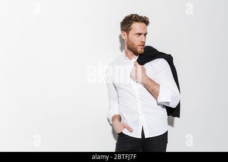 Image of serious man in shirt holding black jacket and looking aside isolated over white background Stock Photo