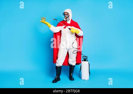 Full size photo of strong power medical worker man hold golden crown use disinfection equipment spray wear red mantle yellow latex gloves goggles Stock Photo