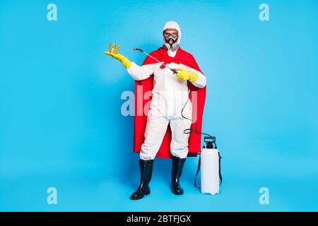 Full length photo of strong power man doctor disinfect gold crown covid virus infection use spray equipment wear yellow latex gloves goggles mantle Stock Photo