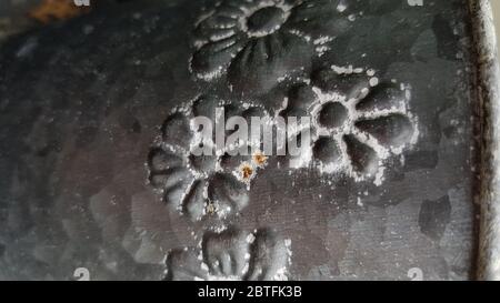 Floral pattern forged ornament of rough grey metal surface closeup. Metallic flowers on steel texture Stock Photo