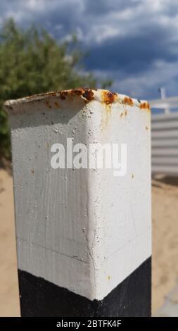 Closeup of old rusty metal pillar painted in white and black colors. White painted metallic surface with rusty drips and stains Stock Photo