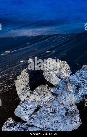 Melting chunk of clear glacial ice, originally calved into Jökulsárlón Lagoon from the Breiðamerkurjökull Glacier, at Diamond Beach on the South Coast Stock Photo