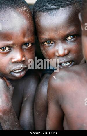 TOPOSA TRIBE, SOUTH SUDAN - MARCH 12, 2020: Kids with dirty skin looking at camera in village of Toposa Tribe in South Sudan, Africa Stock Photo
