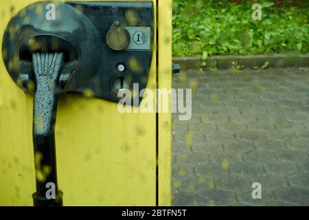 Yellow vacuum cleaner, in parking lot, with a Euro coin slot, photographed through rain window pane, depth of field, Germany. Stock Photo