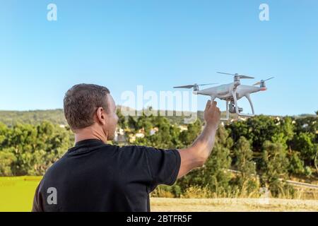 Man, an engineer pilot, a drone, prepares air device for take-off, for testing and filming a vileo and photograph. By controlling the remote. Stock Photo