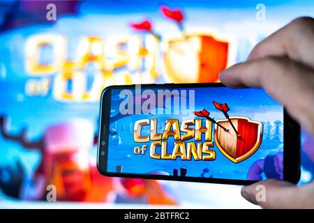 Los Angeles, California, USA - May 25, 2020: Smartphone with the game Clash of Clans on the background of the big screen. Stock Photo