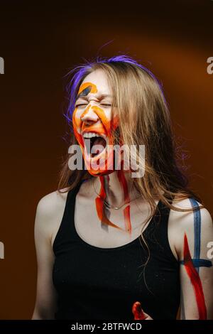 Mighty roar of a young woman with painted face over brown Stock Photo