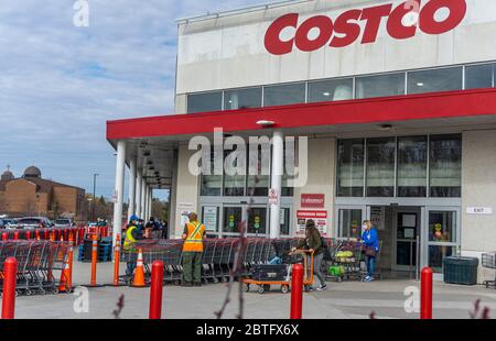 Line up and physical distancing outside of a busy Costco Wholesale, a measure to reduce the spread of Covid-19  Stock Photo
