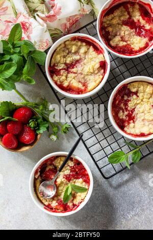 Homemade summer dessert. Strawberries crumble in baking dish on a tabletop made of stone or slate. Top view flat lay background. Stock Photo