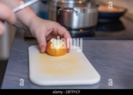 Cropped Hands Of Woman Cutting Onion On Cutting Board At Table Stock Photo