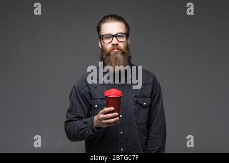 Handsome bearded man with hair beard and mustache on serious face in shirt holding white cup or mug drinking tea or coffee Stock Photo