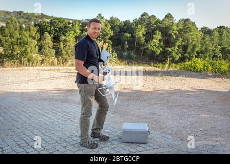 Man, an engineer pilot, a drone, prepares air device for take-off, for testing and filming a vileo and photograph. By controlling the remote. Stock Photo