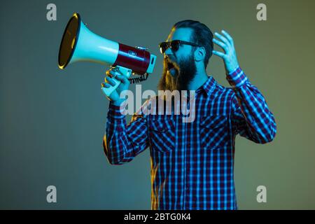 Fashion portrait of emotional hipster man with megaphone on white background in stylish sunglasses. Sales man using megaphone yelling Stock Photo