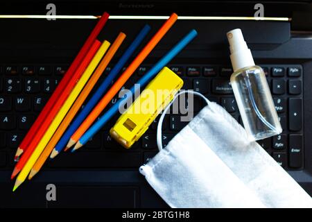 Color pencils, toy school bus, medical mask and hand sanitizer on the keyboard. Flat lay, top view. Back to school concept. School quarantine concept Stock Photo