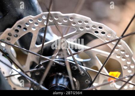 Close-up of a bicycle disc brake system with the metal rotor, calliper, and spokes on a blurred background Stock Photo