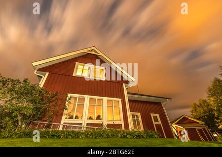 long exposure night photo of traditional red wooden swedish house and dark heavy clouds Stock Photo