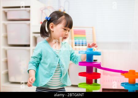 toddler girl play marble run game at home against white background Stock Photo