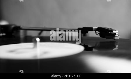 Black and white vinyl needle stylus on rotating black vinyl disk with copy space. Turntable vinyl record player. Stock Photo