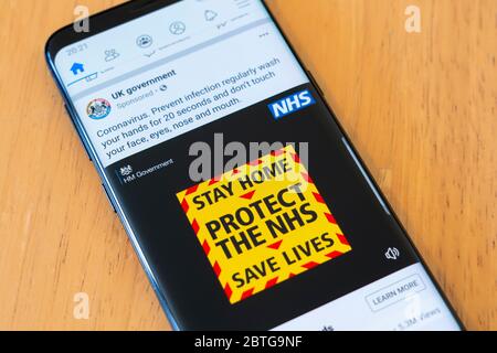 An advertisement from UK Government on a smartphone warning the British public to Stay at Home, Protect the NHS and Save Lives. Covid 19 Coronavirus Stock Photo