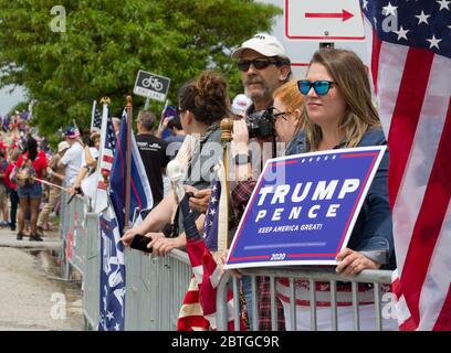 Baltimore, Maryland, USA. 25th May, 2020. Woman wearing mirrored sunglasses among crowd behind barricades holds sign reading 'Trump, Pence, Keep America Great 2020' while another Trump supporter's American flag is draped behind her, outside historic Fort McHenry in Baltimore, Maryland; where President Donald Trump and First Lady Melania Trump visit on Memorial Day 2020 despite urging from Baltimore Mayor Bernard C. “Jack” Young to cancel to avoid setting a bad example while the city remains under a stay-at-home order (with exemptions including some outdoor exercise). Kay Howell/Alamy Live News Stock Photo