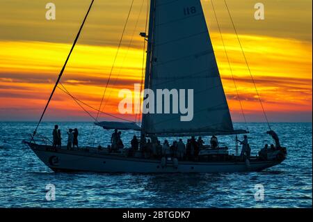 A Sailboat is Full of People Having a Party on the Ocean at Sunset Stock Photo