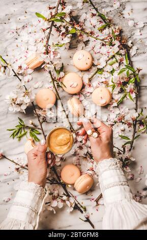 Womans hands holding espresso coffee over macaron cookies and flowers Stock Photo