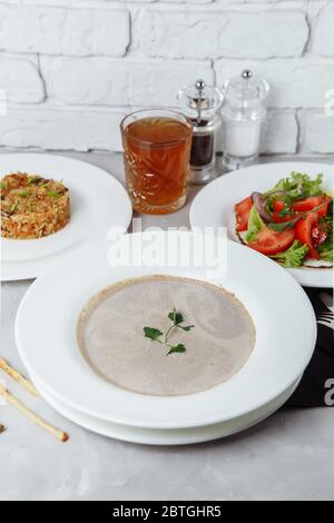 Business lunch from a plate with mushroom cream soup, with chicken and egg, a salad of fresh vegetables and pilaf Stock Photo