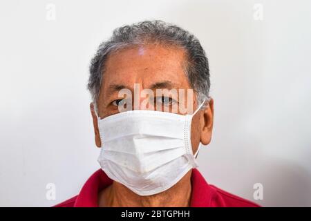Senior Peruvian man suffers from cough with face mask protection, elderly man with facial mask due to air pollution, sick elderly with medical mask, pollution, dust allergies and health concept Stock Photo