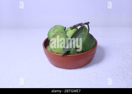 green local fresh mangoes in earthenware on white background. Stock Photo