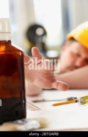 Arm of drunken worker in yellow helmet Stock Photo