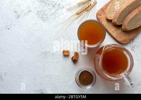 Kvass in a glass and a jug on a light background. Traditional bread drink with rye malt. Top view, place for text. Stock Photo