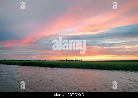 Clouds are illuminated in a beautiful pink by the setting sun and contrast nicely with the blue-gray color of the other clouds Stock Photo