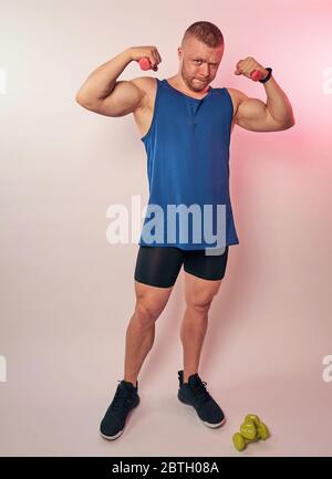 a man with small dumbbells on a light background Stock Photo