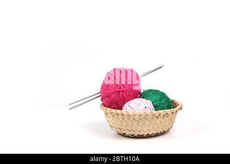 clews of different colours and knitting needles in wicker basket isolated on white background. Image contains copy space Stock Photo