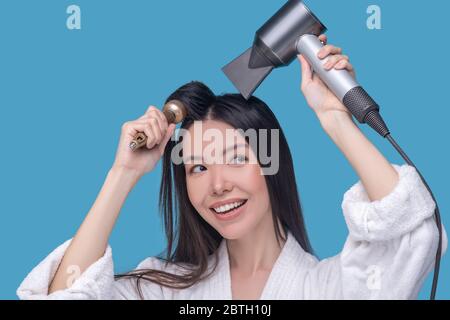 Brunette young asian woman drying her hair and smiling Stock Photo