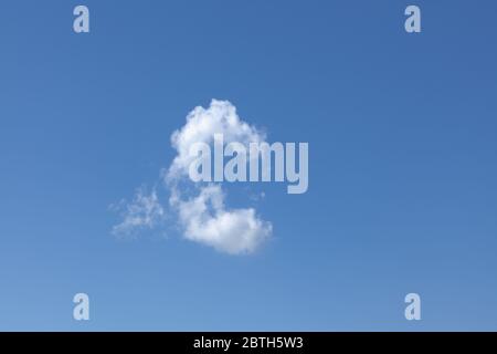 One white wispy cloud in a beautiful blue sky background. Cloudscape view on a clear day. Stock Photo