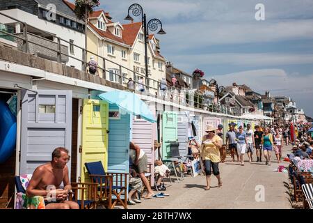 Holiday beach huts and tourists enjoy the English sunshine, Lyme Regis, Dorset, England, United Kingdom Stock Photo