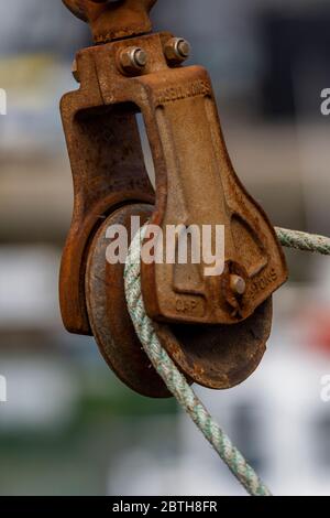 a rusty and corroded old pulley block and wire rope on a fishing trawler. Stock Photo